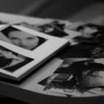 A collection of black and white photos scattered on a table, featuring portraits and artistic compositions.